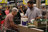 An older woman at a checkout in a supermarket