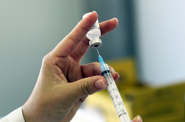 Hand withdrawing medicine into needle.