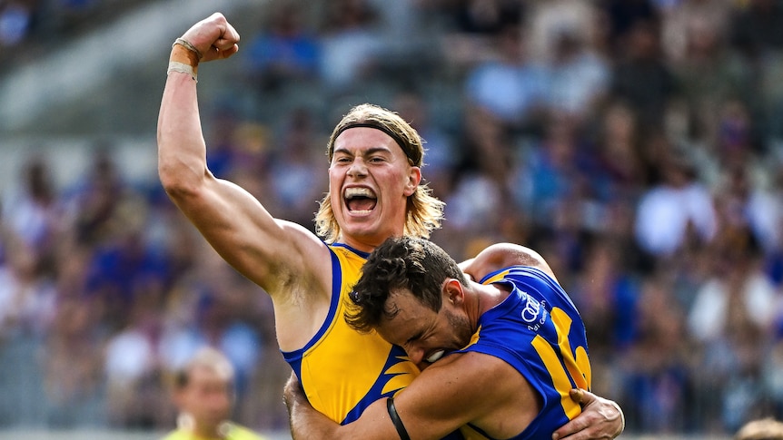 Harley Reid, pumping his fist, being hugged by a teammate, during an AFL match