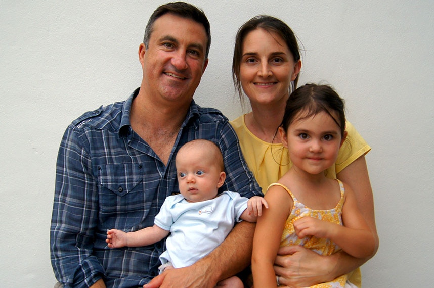 Parents and their two young children sit on a bench