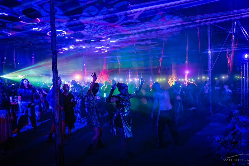 People dancing at night on a dance floor lit by blue lights