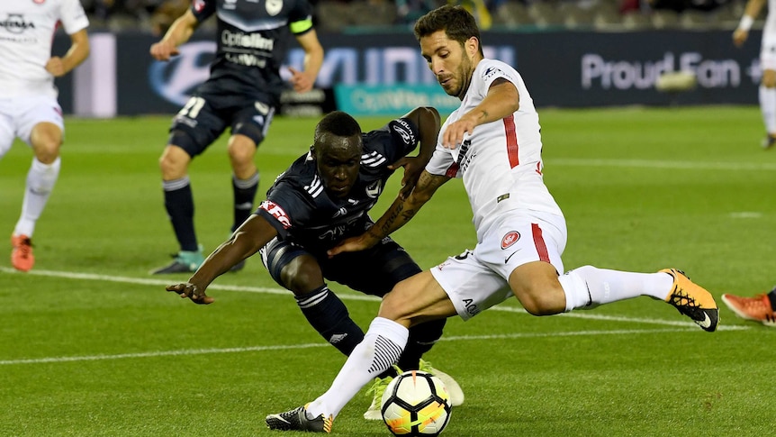 Thomas Deng of Melbourne Victory tries to intercept the ball from Alvaro Cejudo from the Wanderers as he goes in for a strike.