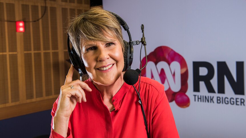 Woman in radio studio with headphones and microphone on head.