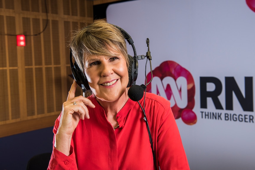 Woman in radio studio with headphones and microphone on head.