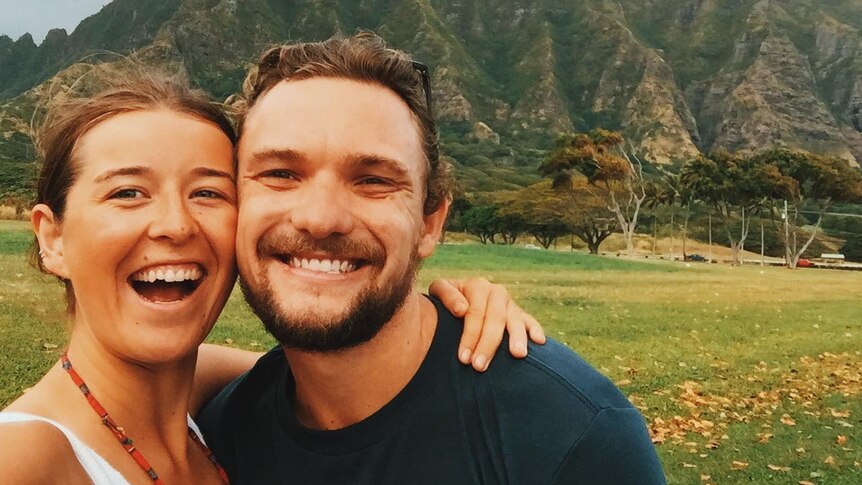 Bridget Lindsay and Ben Evans smiling while standing in front of a green mountain