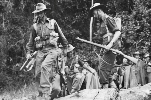 Black and white photo of Australian soldiers in the jungle carrying guns and bags