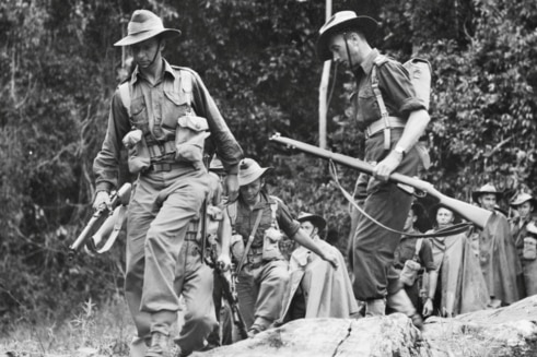 Black and white photo of Australian soldiers in the jungle carrying guns and packs