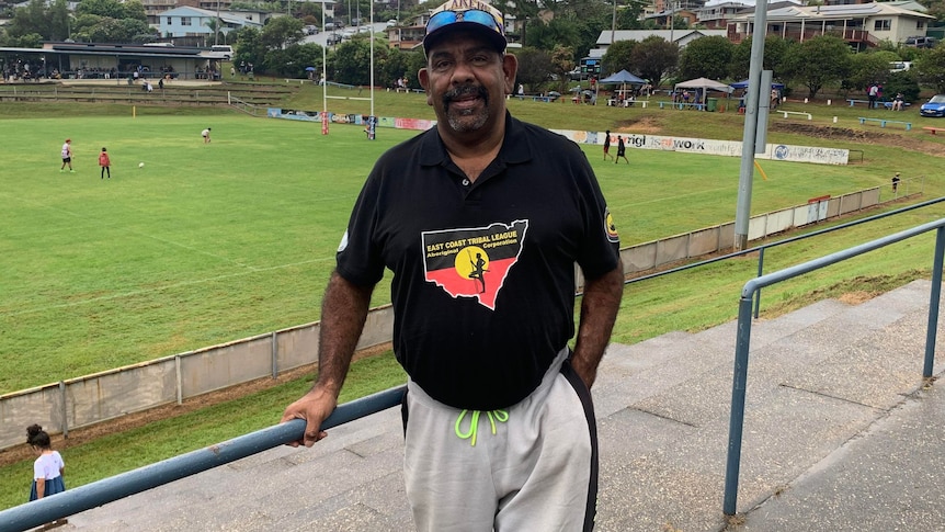 Paul Davis stands in front of rugby league field wearing East Coast Tribal League merchandise
