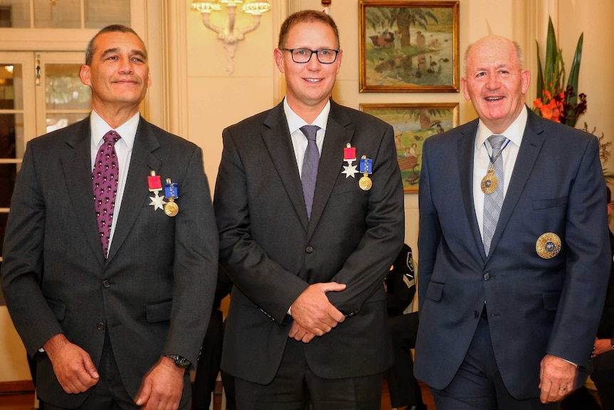 Richard Harris and Craig Challen, wearing their medals, pose for a photo with Governor-General Sir Peter Cosgrove.