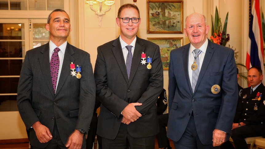 Richard Harris and Craig Challen, wearing their medals, pose for a photo with Governor-General Sir Peter Cosgrove.