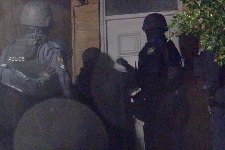 Police raid a property in Sydney and are seen bashing on a door.