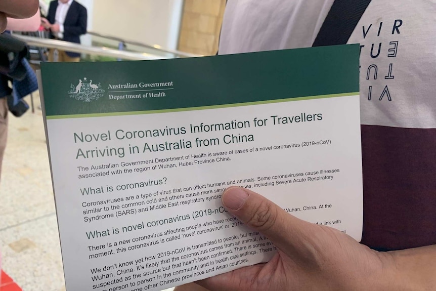 A man holds an information sheet on coronavirus