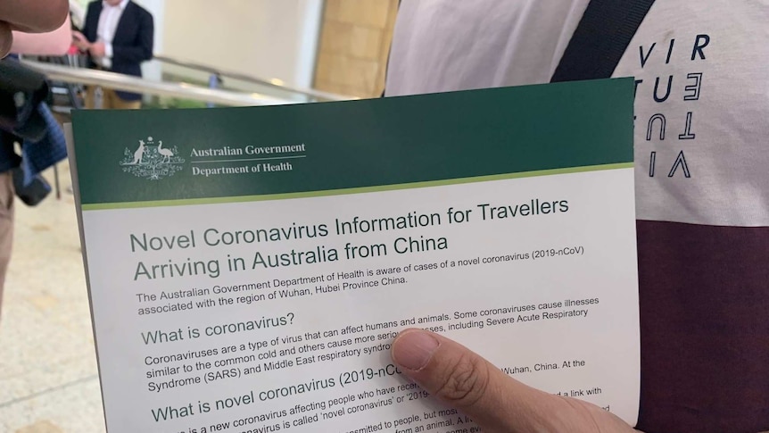 A man holds an information sheet on coronavirus
