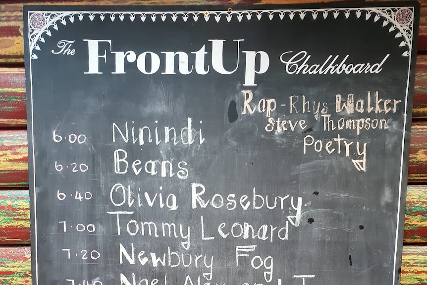 A chalkboard with performers' names in white chalk