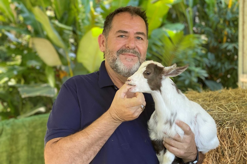 Goat breeder Rodney Surawski holding a Nigerian Dwarf kid.