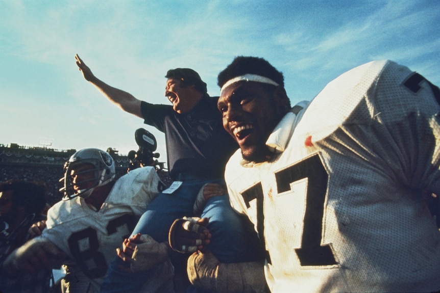 Un entrenador de la NFL es llevado sobre los hombros de sus jugadores en señal de triunfo después de que su equipo gana el Super Bowl.