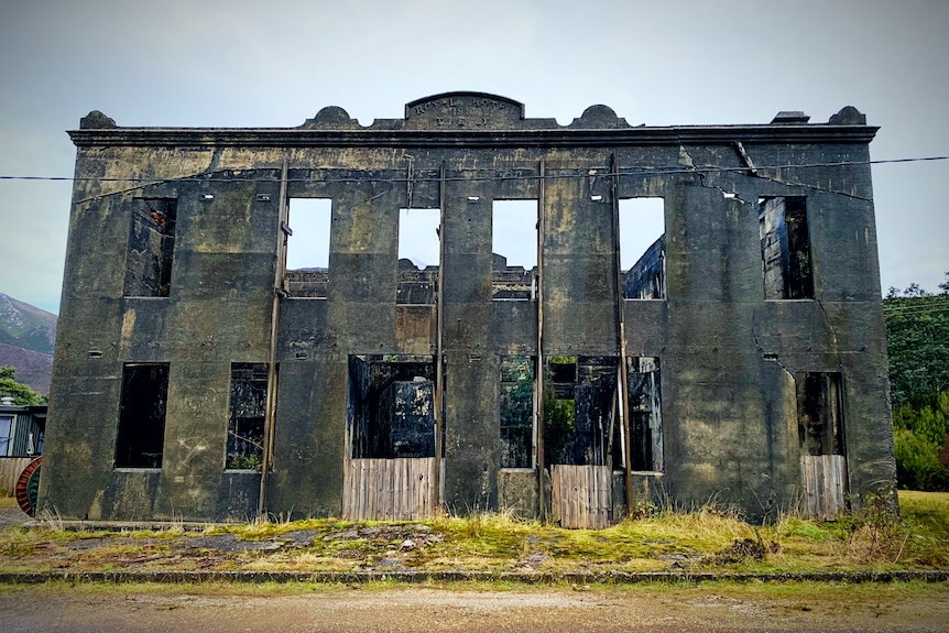 A dark grey two story concrete ruin of a hotel 