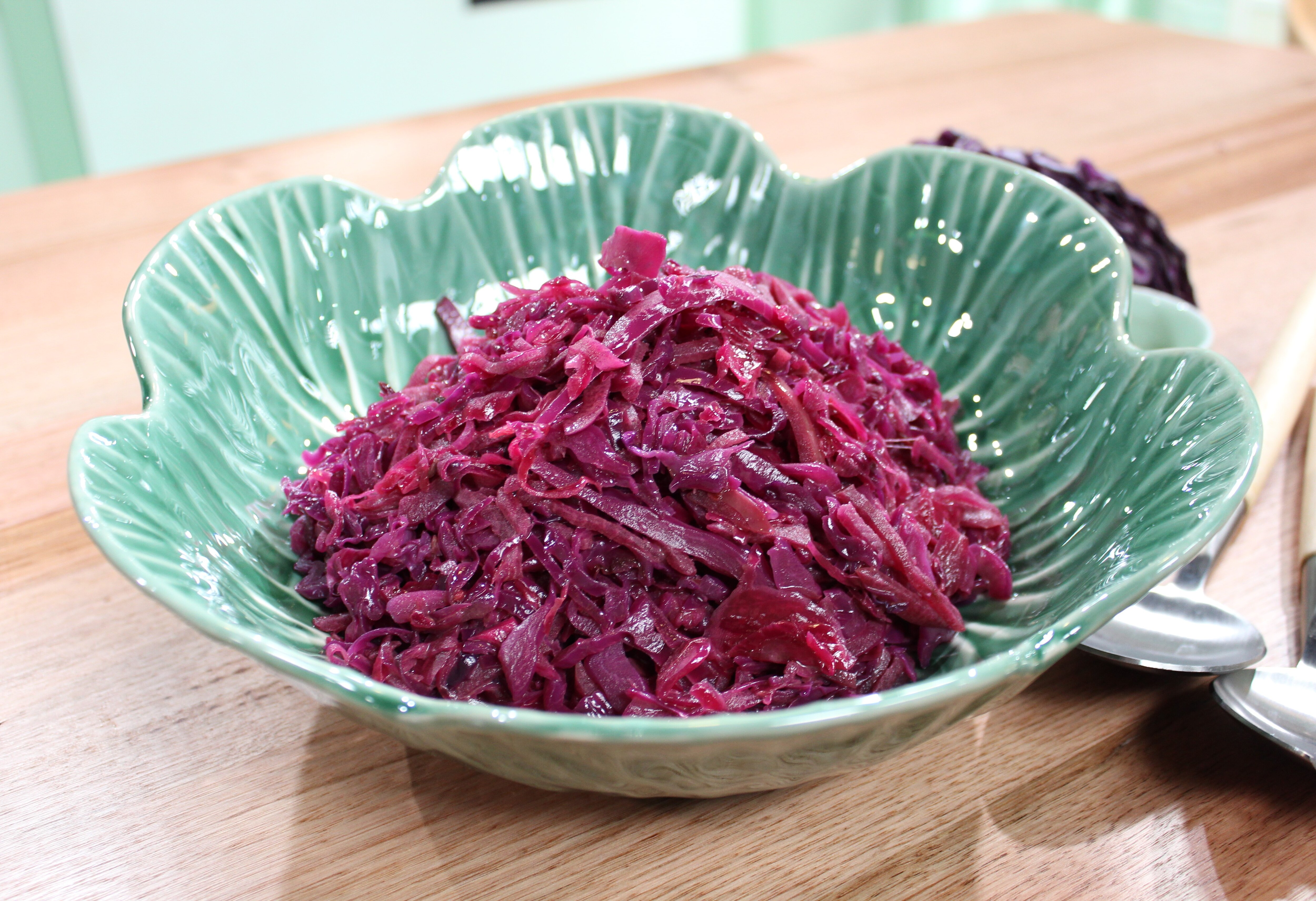 A green bowl with bright red wilted cabbage in it