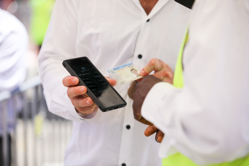 A man shows his license and phone as proof of vaccination against COVID-19.