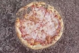 A whole pizza surrounded by a mass of thousands of maggots.