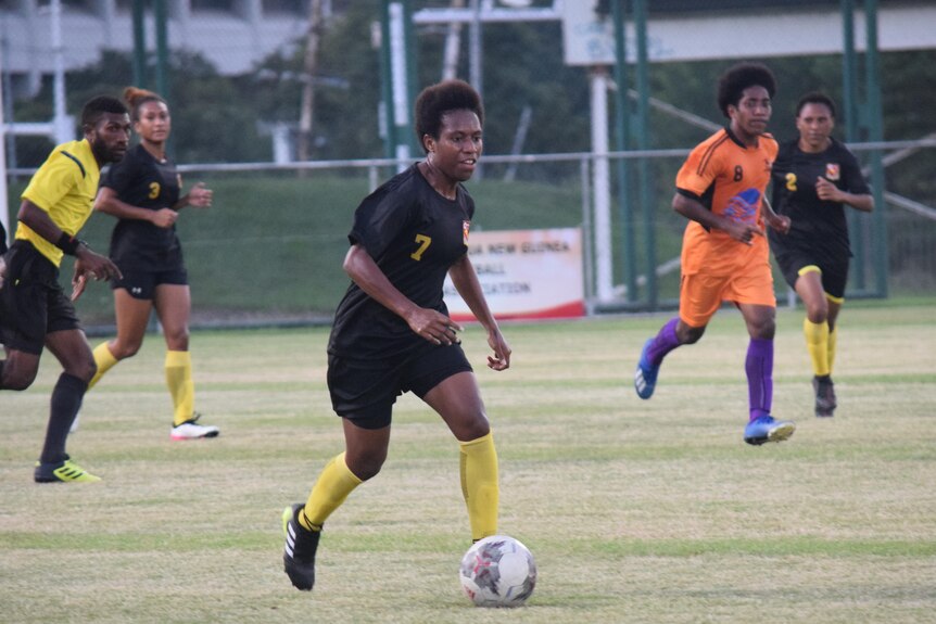 Yvonne Gabong from the PNG women's national football team runs alongside a soccerball at training.