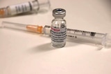 Two syringes and a small glass vial of vaccine.