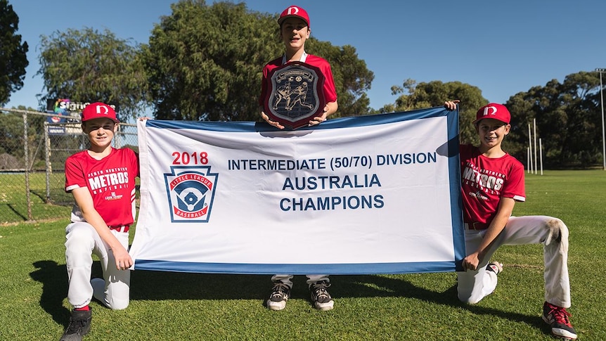 Perth Little league players hold up a banner and shield.