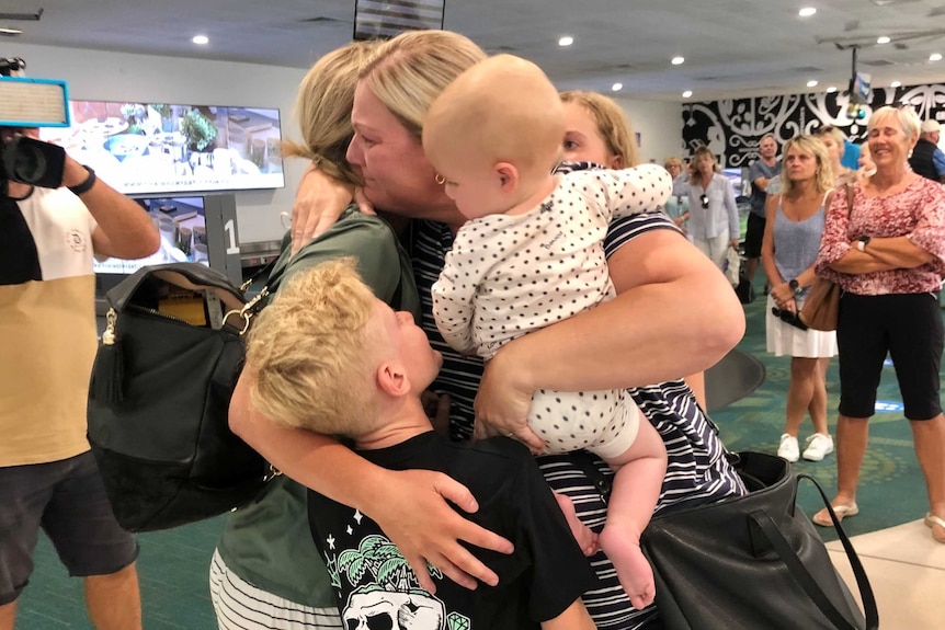 A family hug and cry in an airport.