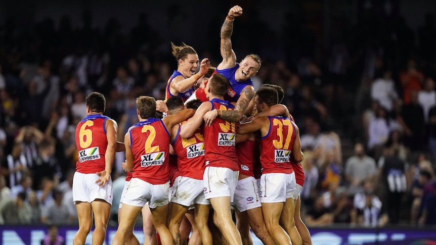 Aussie rules players jumping on each other in celebration after winning a match.