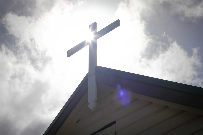 The cross atop St James Church, Bungwall, with the sun behind it