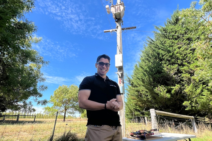 A man standing in front of a power pole.