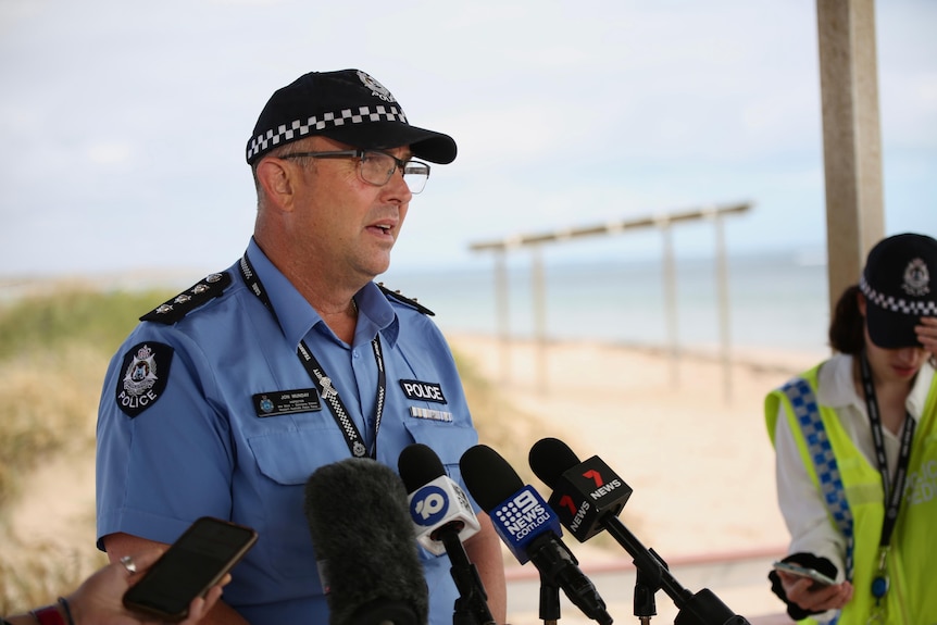 A police officer talks before a series of microphones