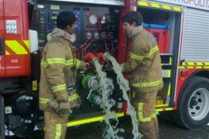 Fire fighters empty green-tinted water from a fire truck