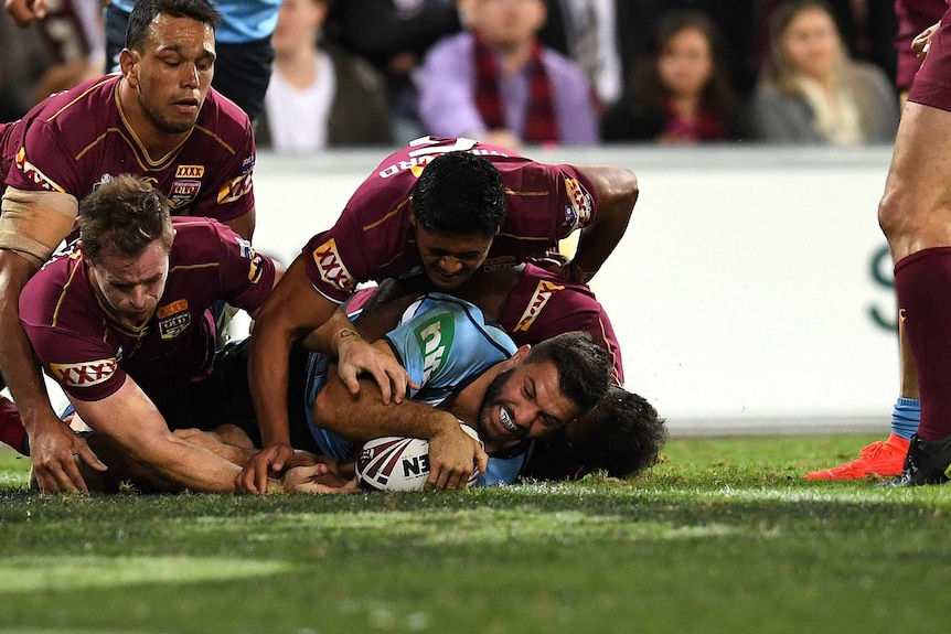 James Tedesco is covered by the Maroons defence after touching down for a Blues try.