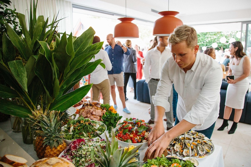 Alex Cadger arranging food on a table at an event.