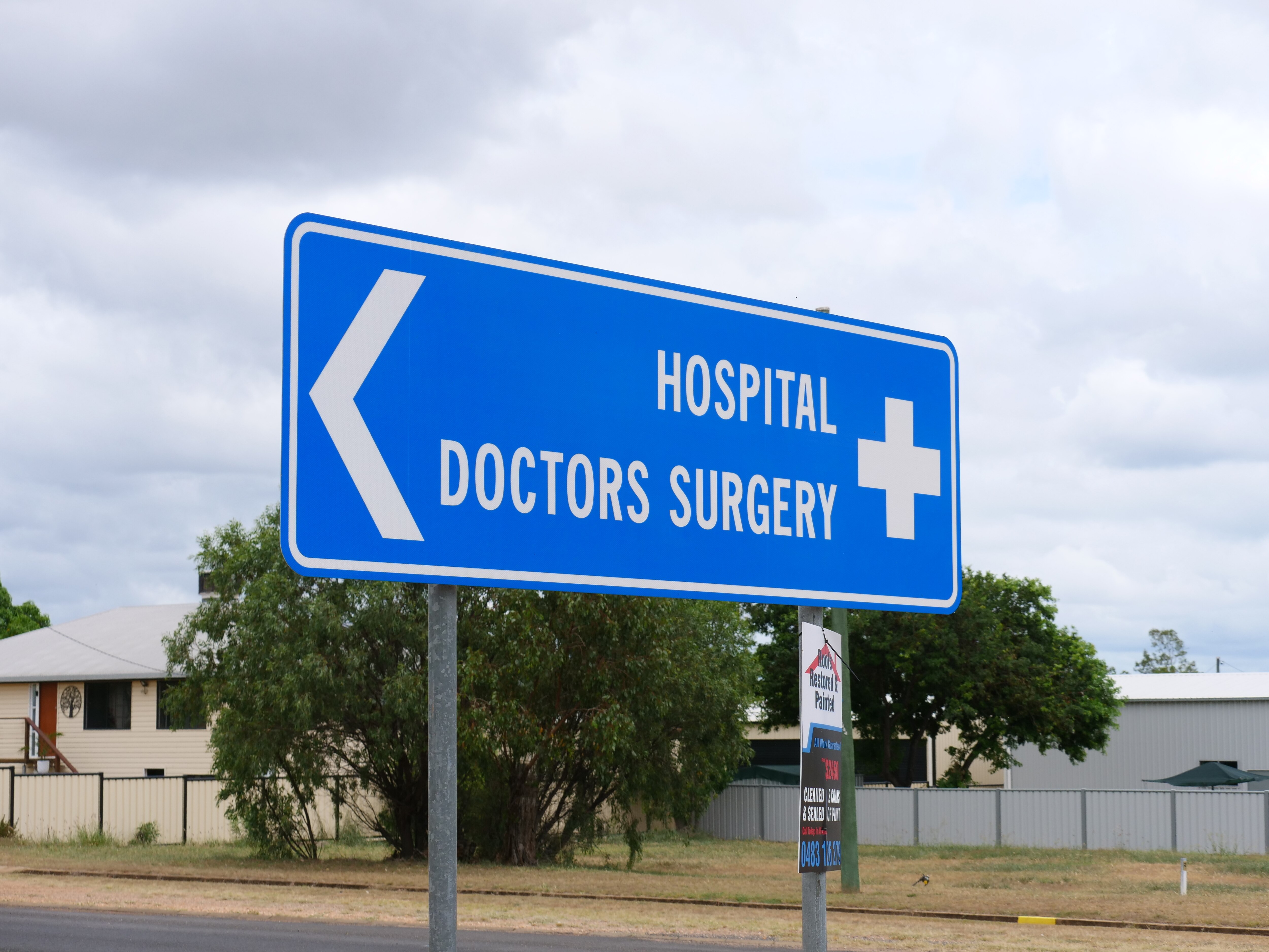 A blue street sign that says hospital and doctors surgery with an arrow pointing left