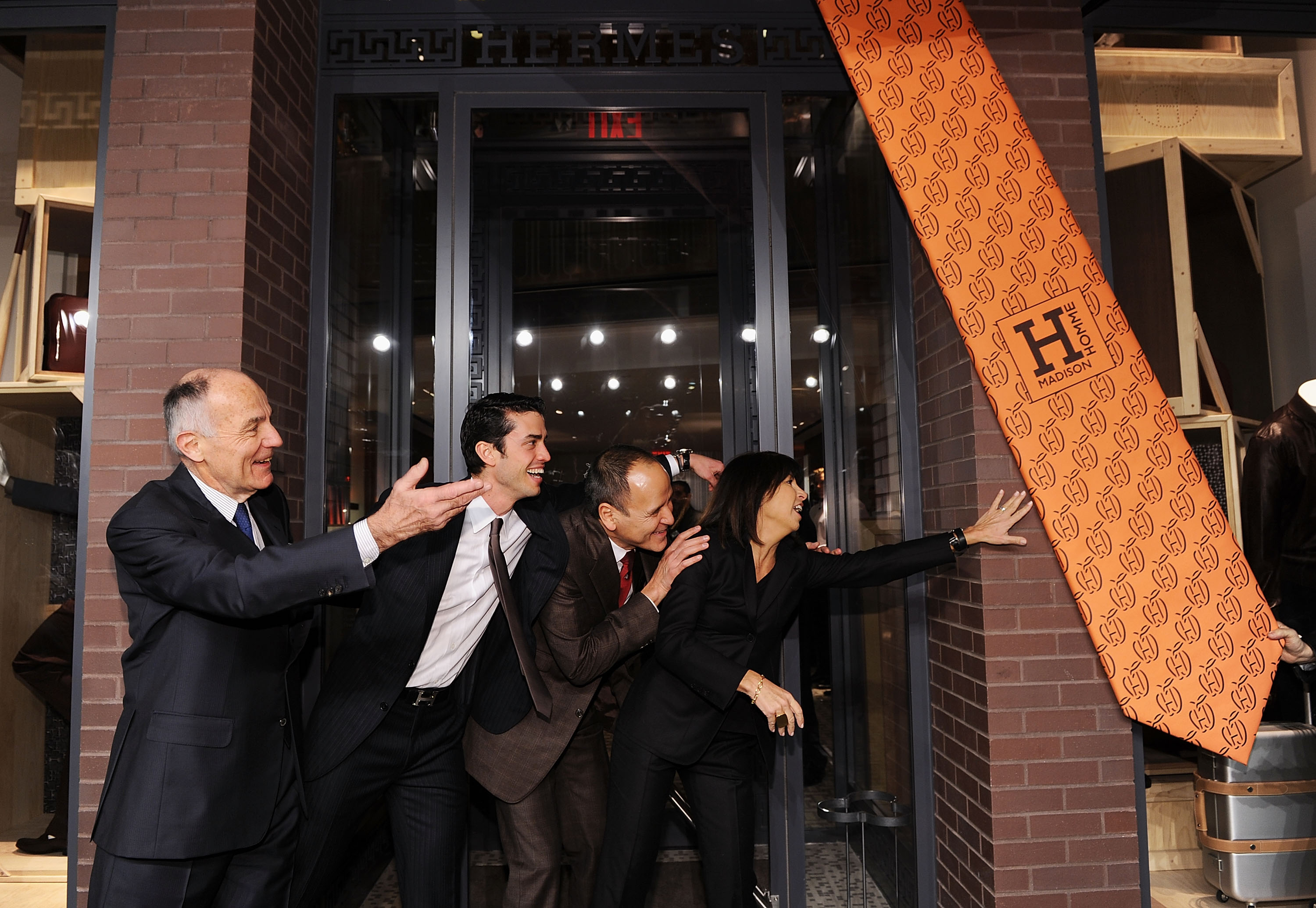 A group of people gesturing at a giant swinging orange tie 