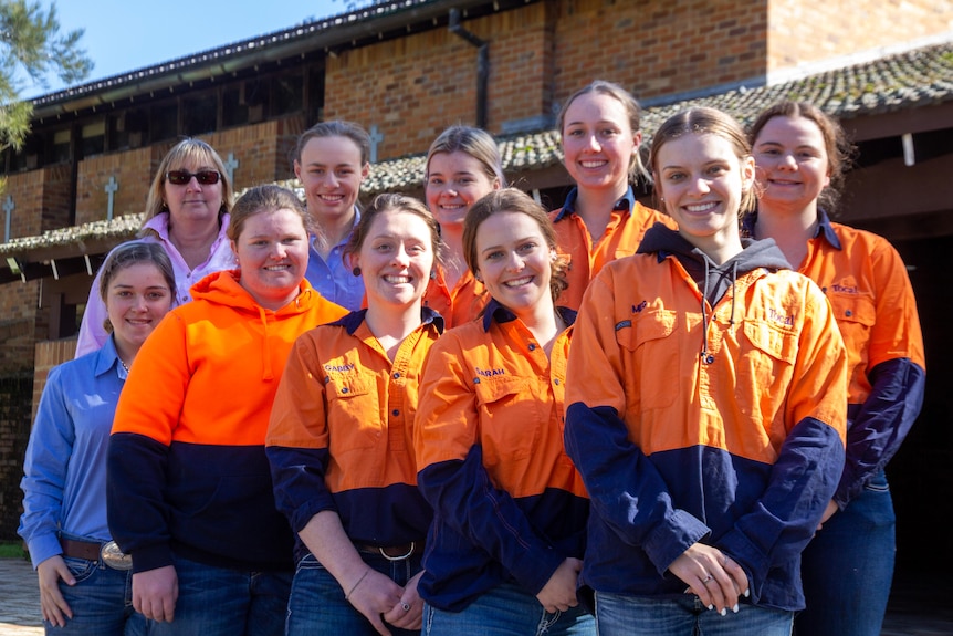 A group of women stand together on the steps of Tocal College and smile at the camera