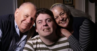 A young man in the centre surrounded by his parents.