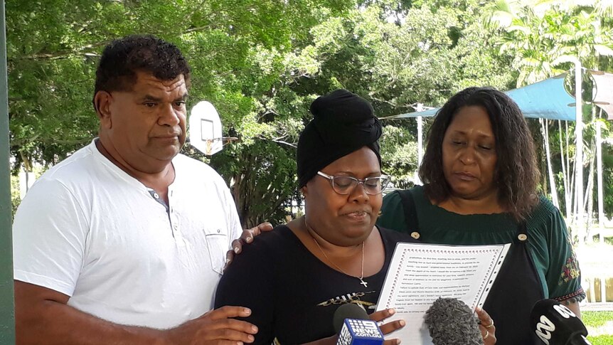 Family stand in front of microphones while reading a statement.