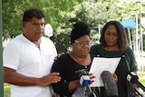 Family stand in front of microphones while reading a statement.