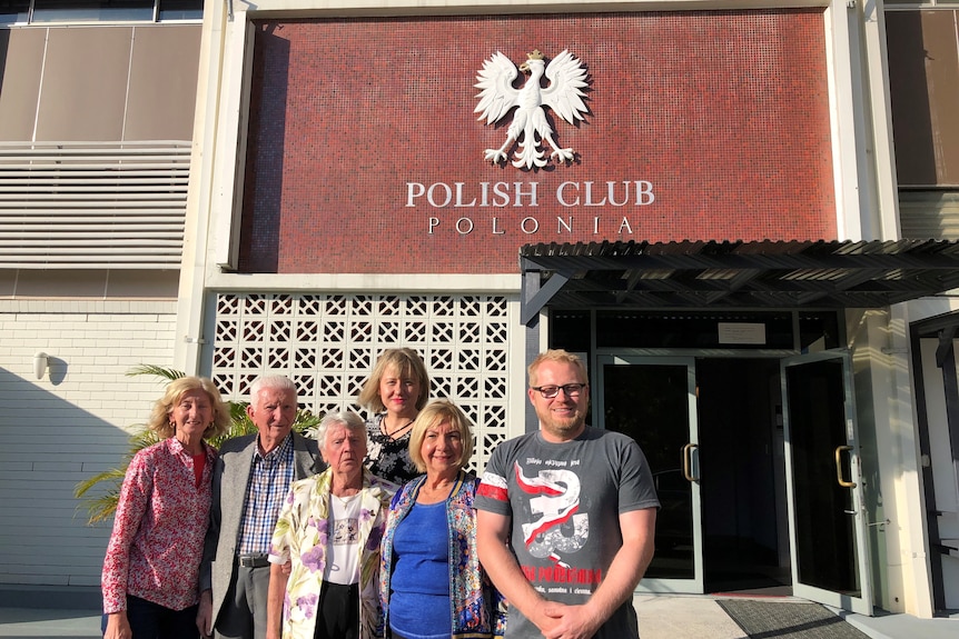 A group of people stand outside a club.