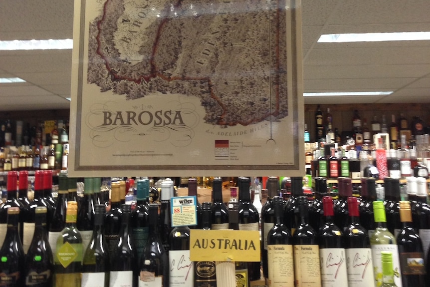 Australian brands of wine sit on a shelf beneath a large map of the barossa valley