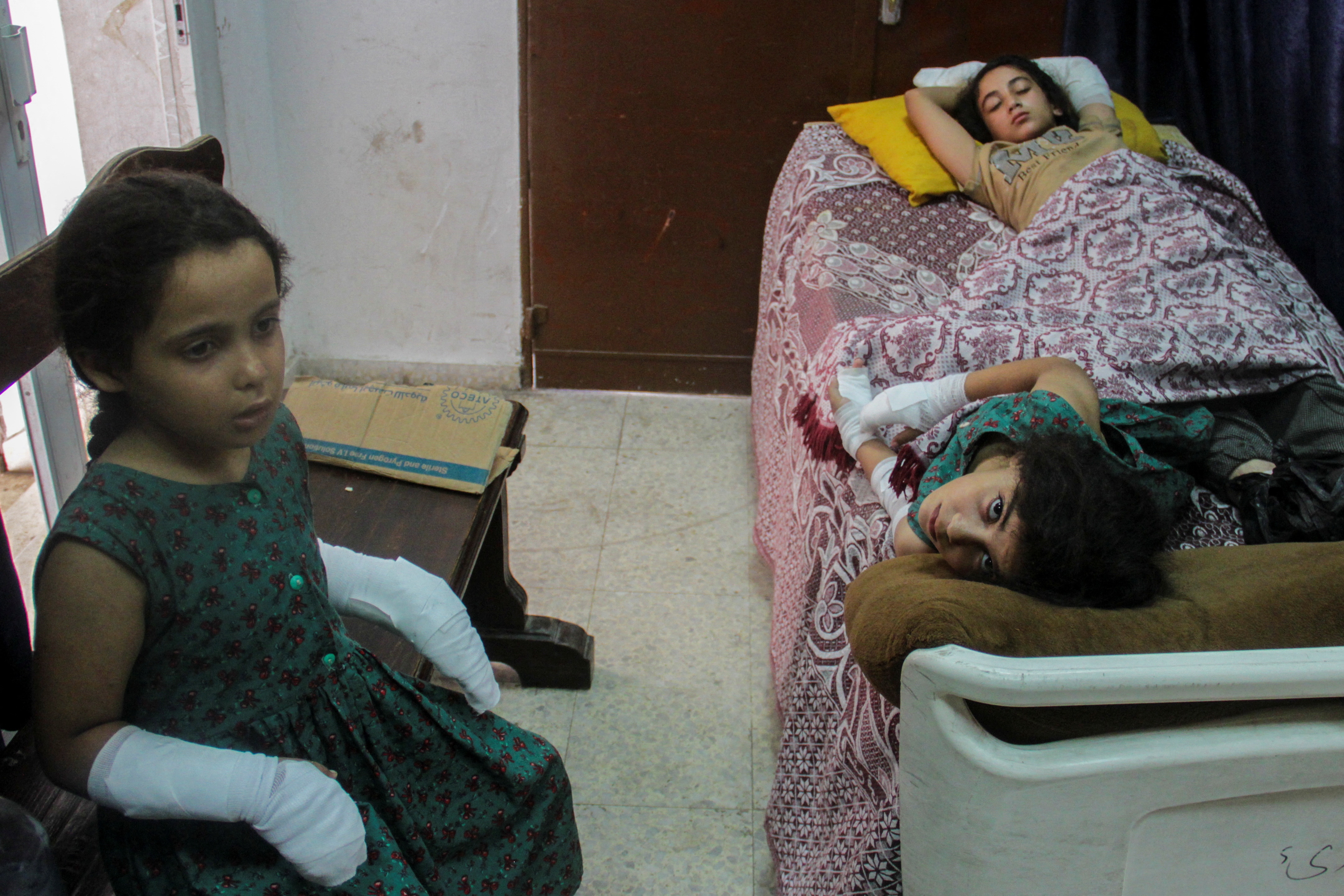A little girl sits on seat with casts on both hands 