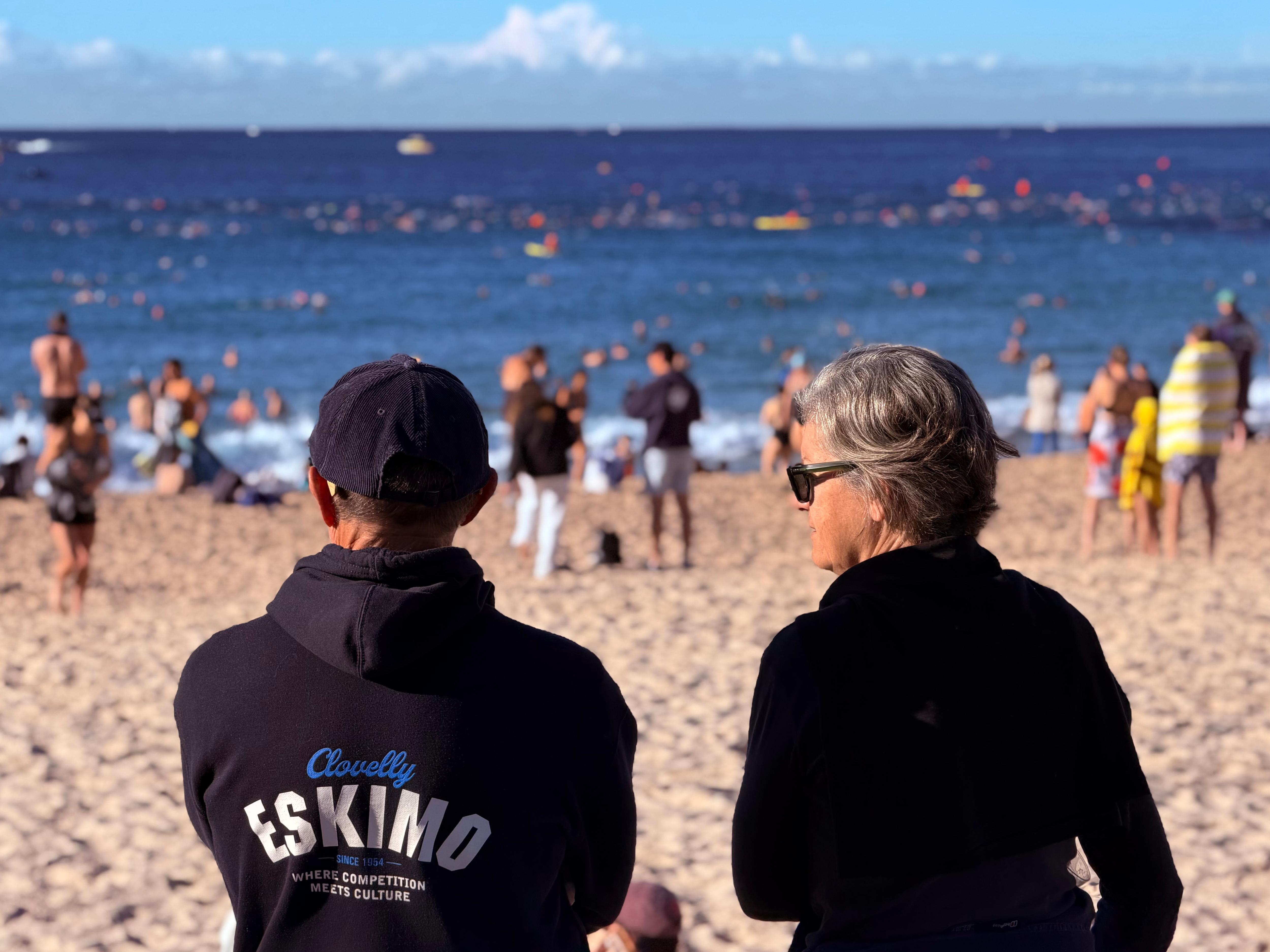 Two people standing on the sand watching the swim-out.