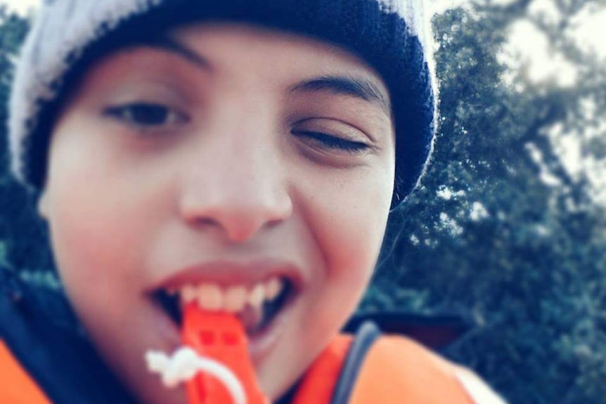 A boy wears a life jacket holding an attacked whistle.