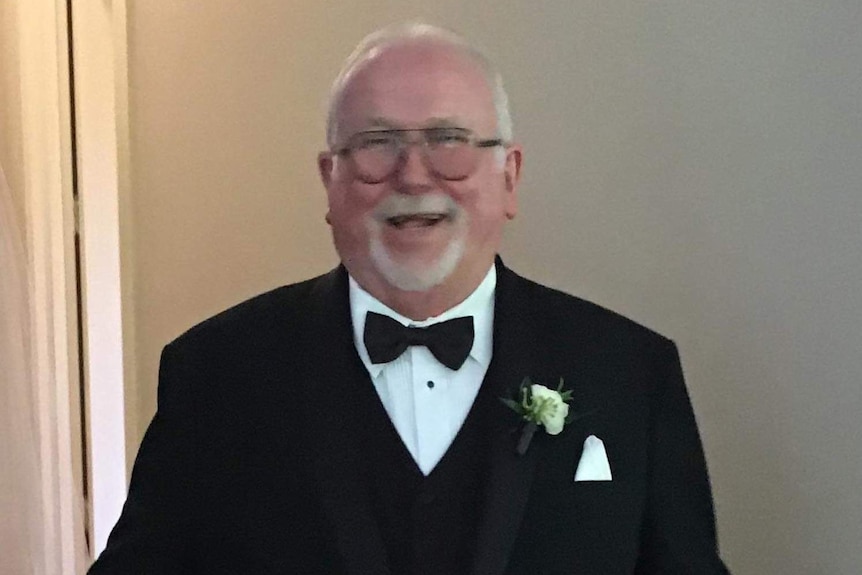A mid shot of Tony Hickey laughing and smiling wearing a black tuxedo and bowtie.