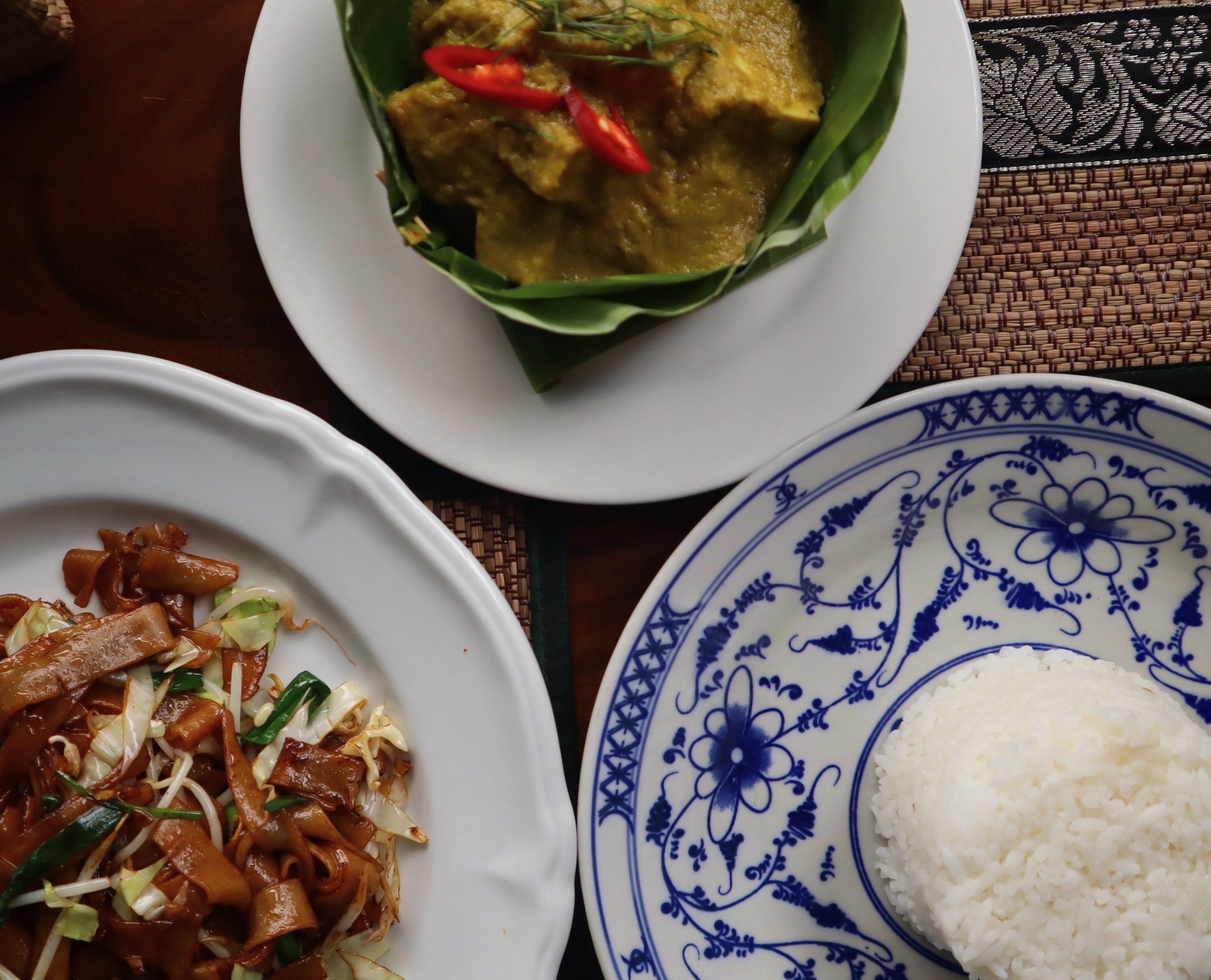A plate of rice, amok curry, and stir fried noodles.