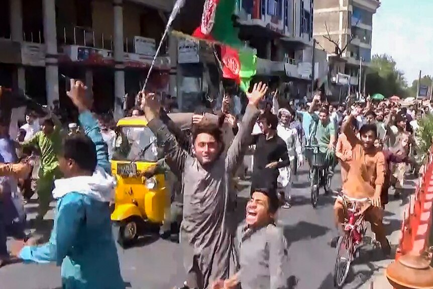 People holding the Afghanistan flag running on the street
