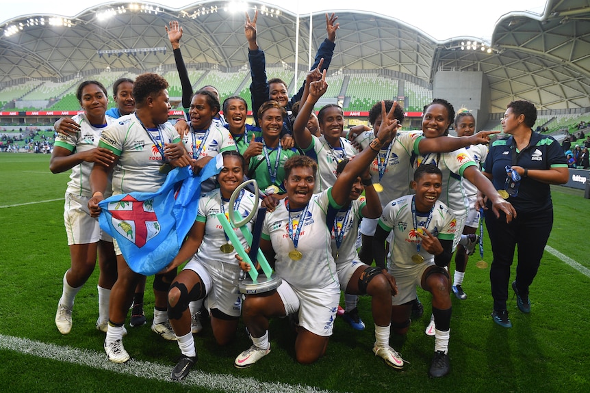 A women's rugby team celebrates together. 